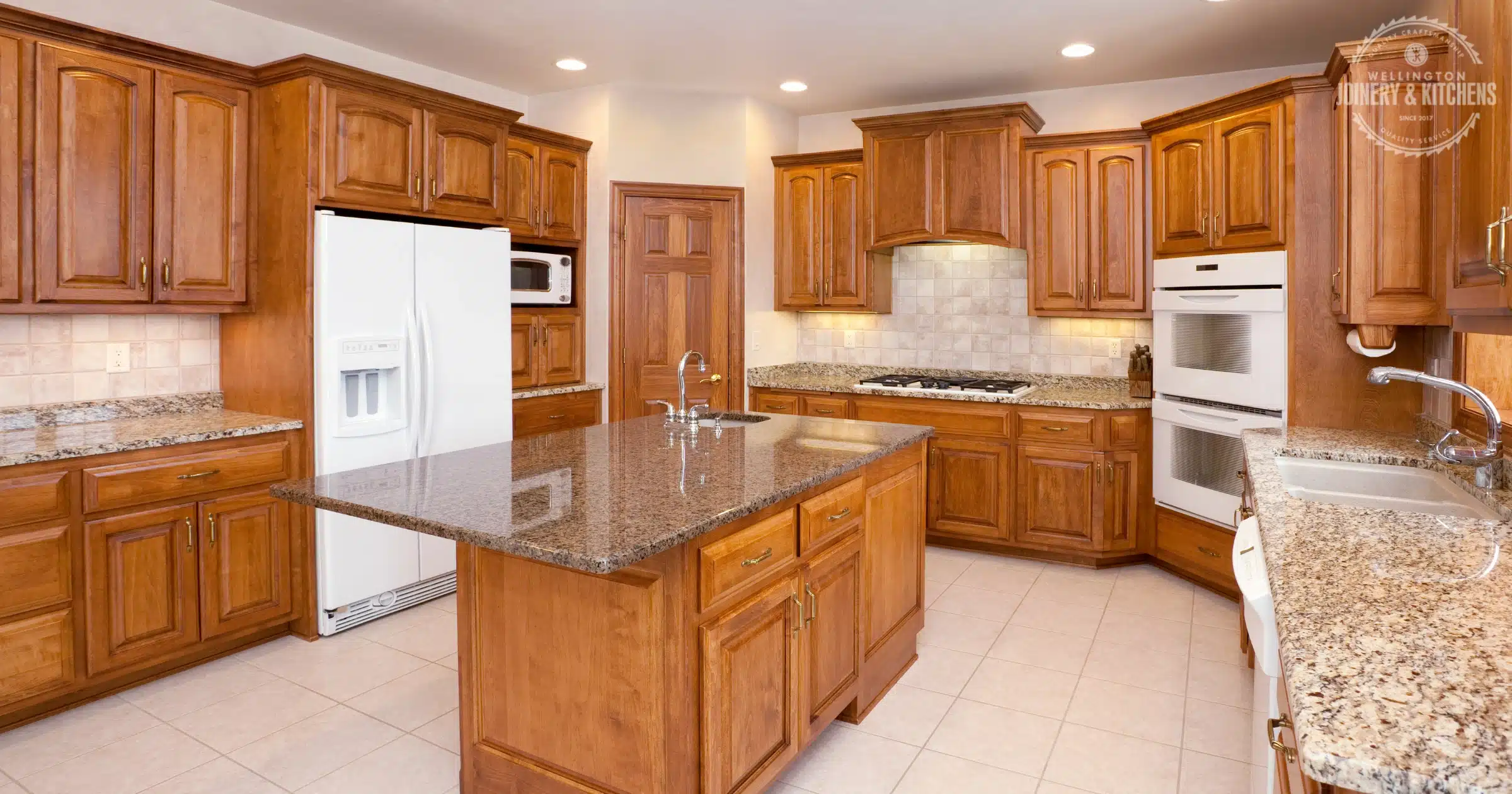 Custom kitchen with wood cabinets, white tops, and pendant lights.